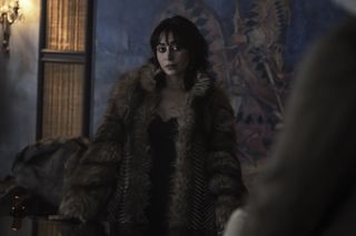 A photo of Sofia Falcone from The Penguin in a faux fur coat and black lace slip dress