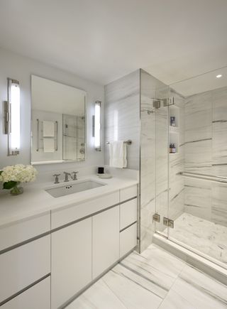 A modern bathroom with a white vanity and marble tiles