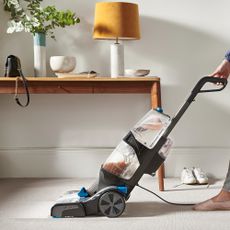 A hallways with a sideboard being vacuum cleaned