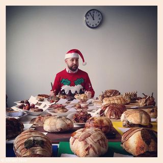 Man in Christmas jumper in front of a table full of festive food