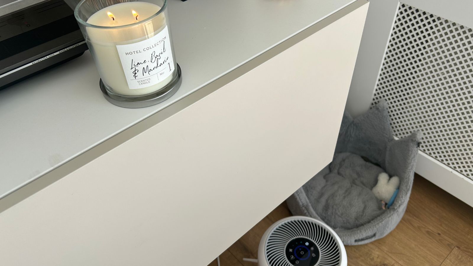 Air purifier in living room by dogs bed and with candle on sideboard