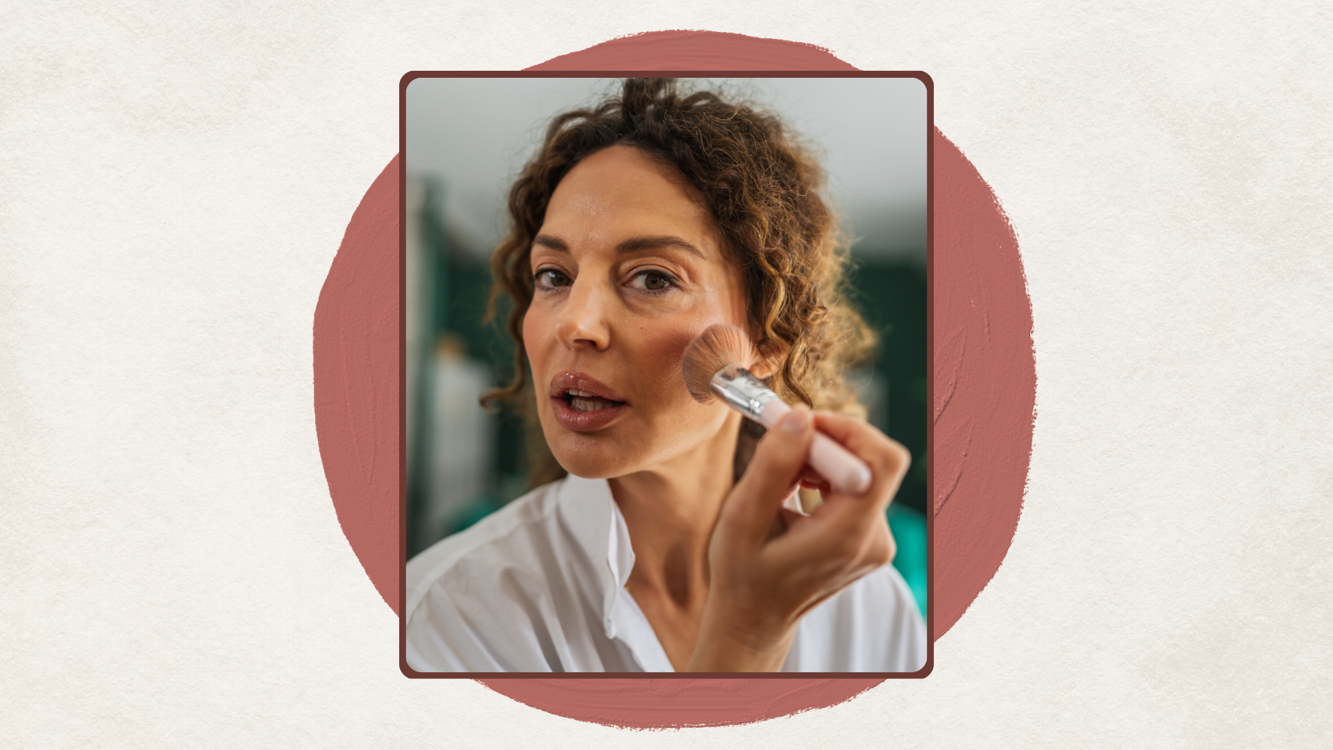 Vertical image of woman applying blush set against a rust-coloured abstract shape on a beige background