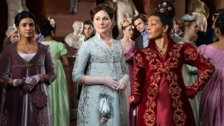 (L to R) Shelley Conn as Mary Sharma, Ruth Gemmell as Lady Violet Bridgerton, Adjoa Andoh as Lady Danbury wearing a red and gold dress.