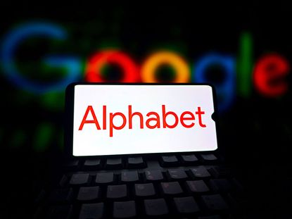 Alphabet logo displayed on a smartphone screen with Google script in the background