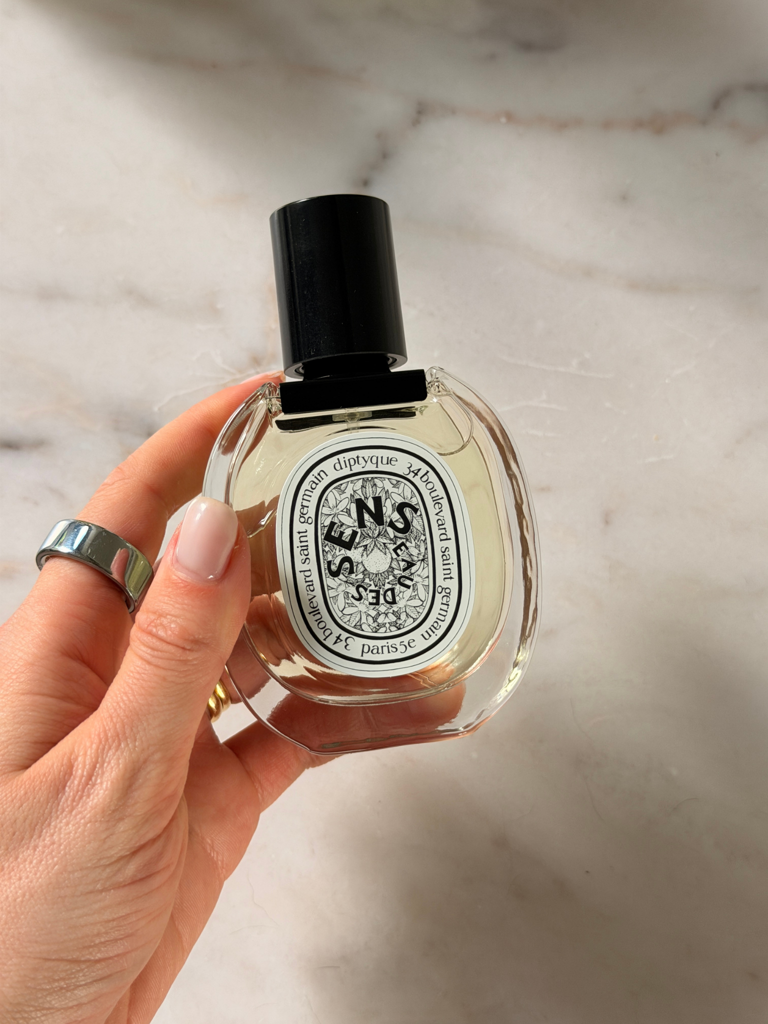 Grace holding a bottle of Diptyque perfume