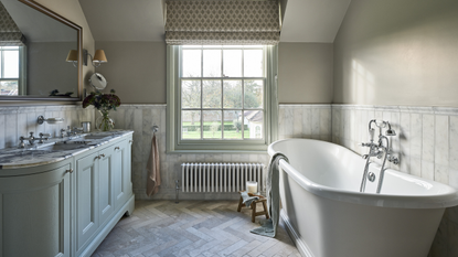 beautiful light and airy bathroom with a free standing roll top bath marble tiles and a double sink 