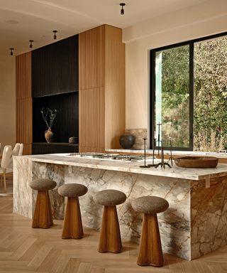 modern kitchen with marble island and button stools with wooden floorboards