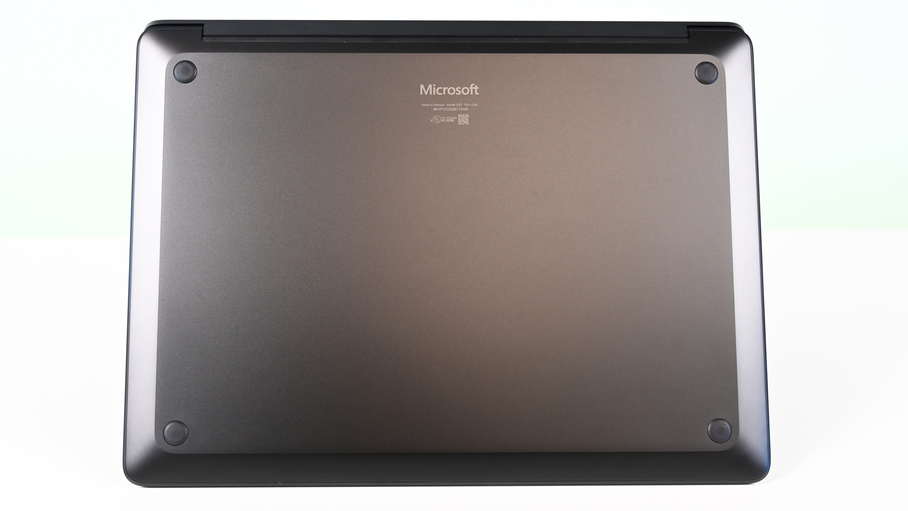 A closed Microsoft Surface Laptop for Business 8th Edition viewed from the bottom, showing a sleek gray finish and four round rubber feet on a minimalistic design.