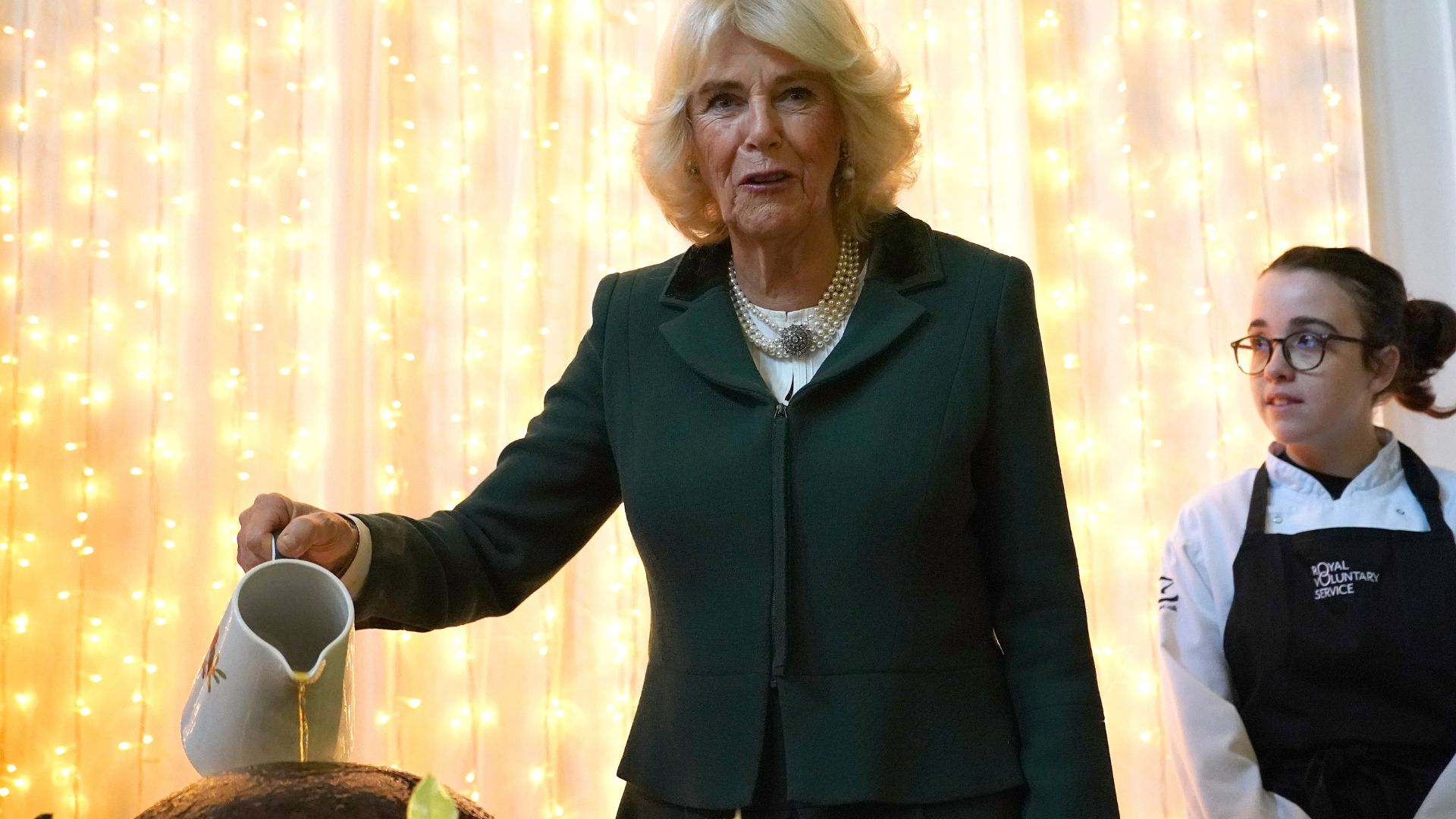 Queen Camilla pouring brandy over a christmas pudding in 2024