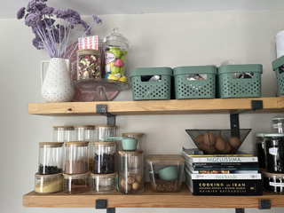 Blue platic storage baskets on open shelving above glass food storage jars