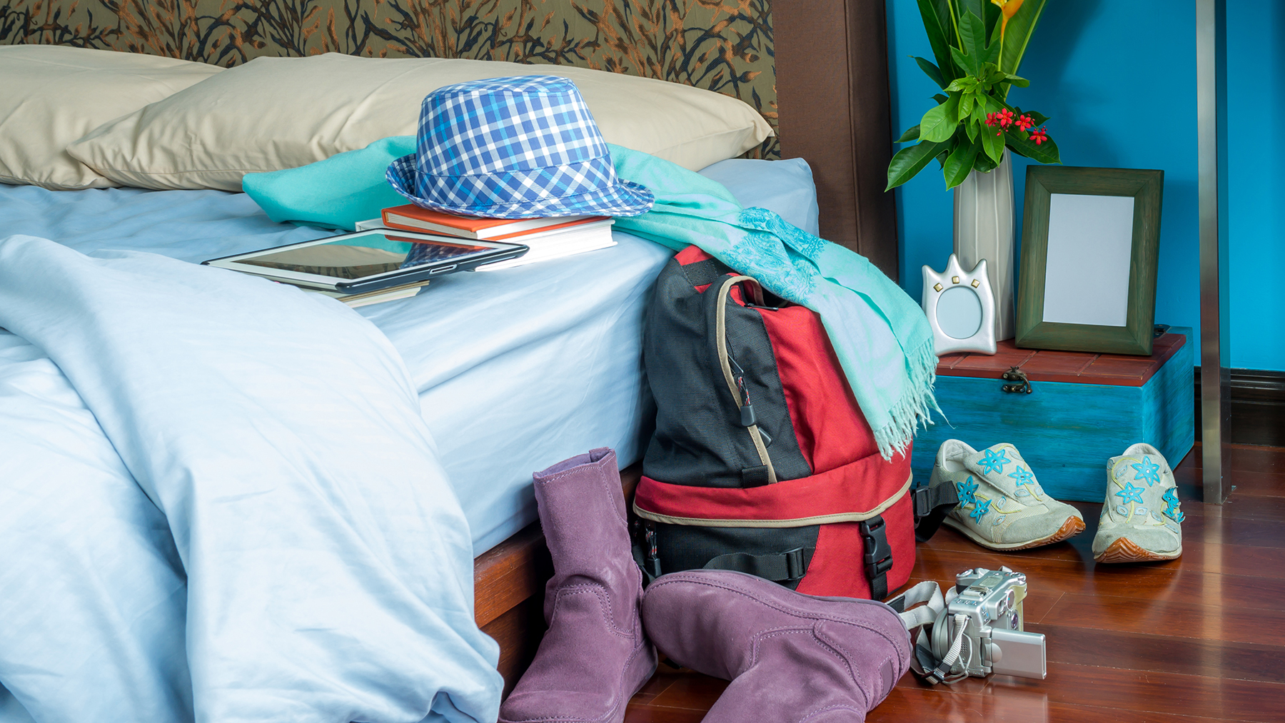 Messy bedroom with an unmade bed and a bag and clothing on floor