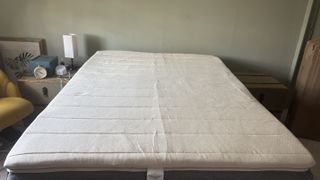 The Birch Plush Organic Mattress Topper on top of a memory foam bed in a light green bedroom.