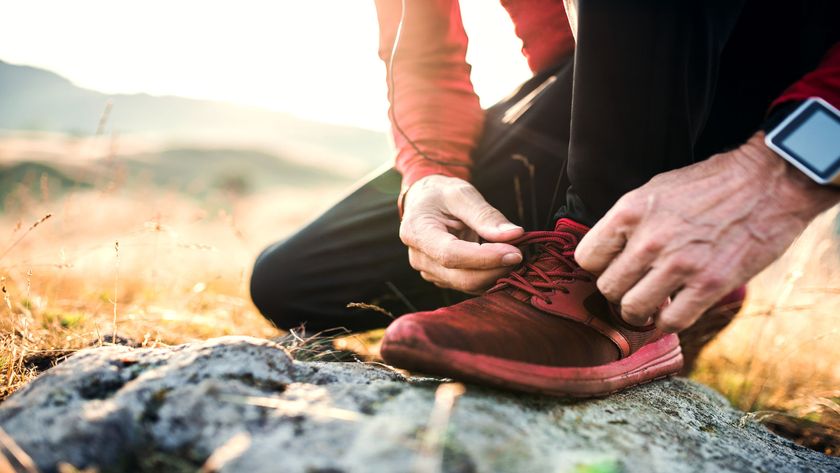 A close up of a trail runner tying up their red running shoes