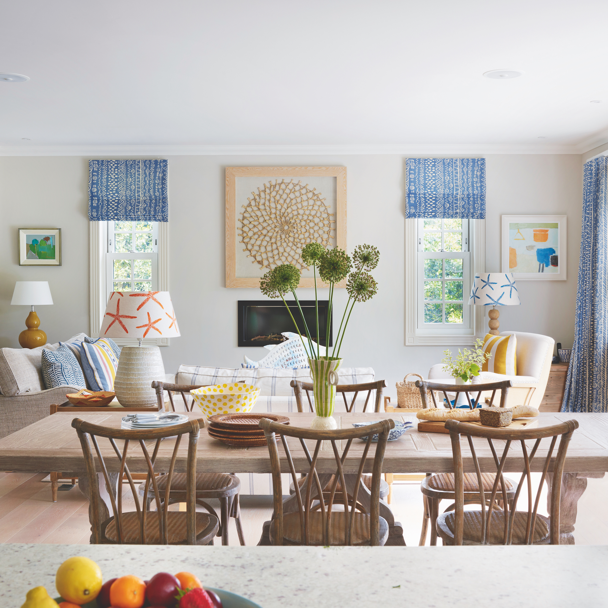 dining tabl with six wooden chairs and seating area behind with sofa, armchair and inset fireplace
