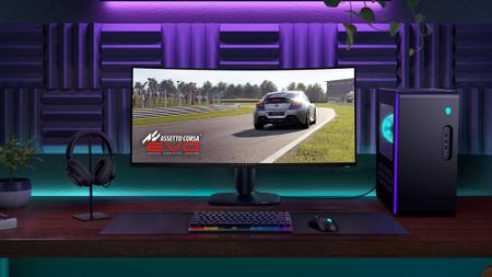 Alienware AW3425DW monitor on desk next to Aurora R16 desktop PC with purple backdrop and Assetto Corsa EVO art on screen.