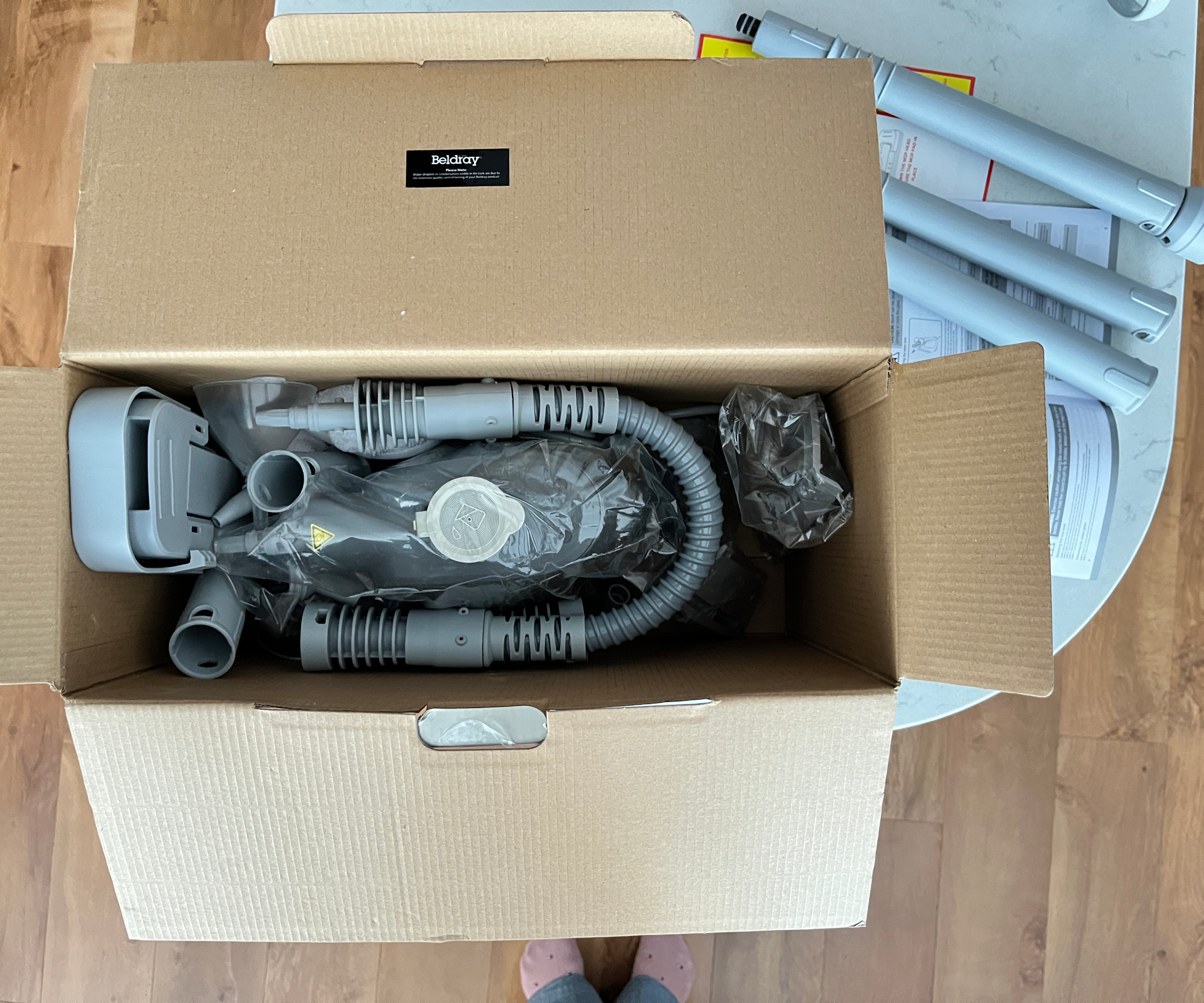 inside of an open box containing various parts of steam cleaner