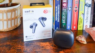 EarFun Air Pro 3 wireless earbuds sitting in their case, next to their box, on a shelf.