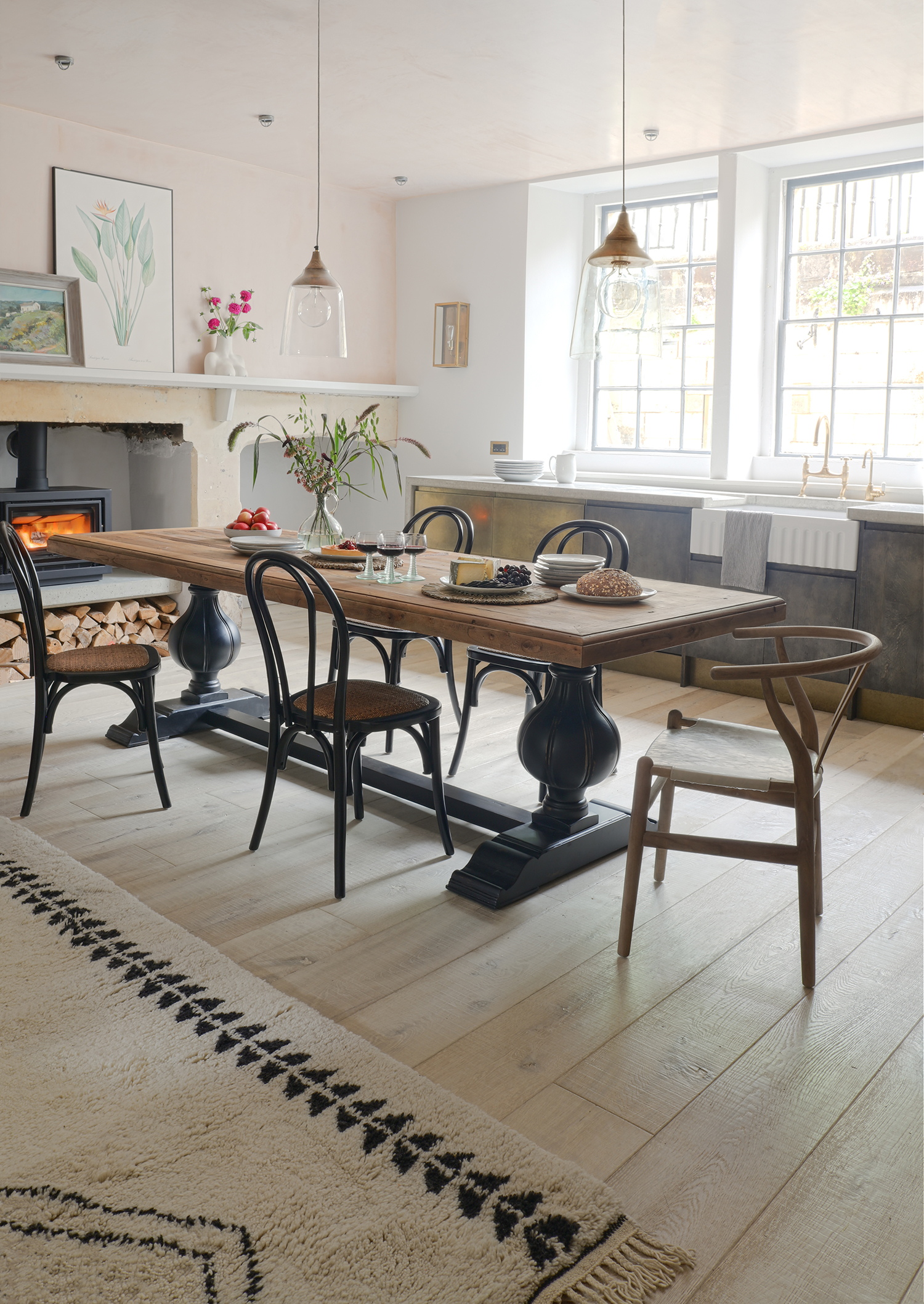 rustic dining room with black chairs, log burner, rug, floorboards