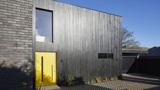 contemporary timber clad house with yellow front door