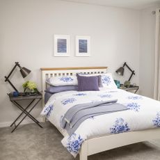 bedroom with photoframe on white wall and floral printed white bedding set 