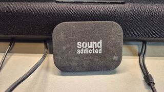 A picture of a sound addicted soundbar isolation pad resting against a Yamaha soundbar on a gaming desk