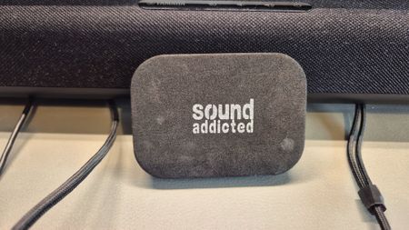 A picture of a sound addicted soundbar isolation pad resting against a Yamaha soundbar on a gaming desk