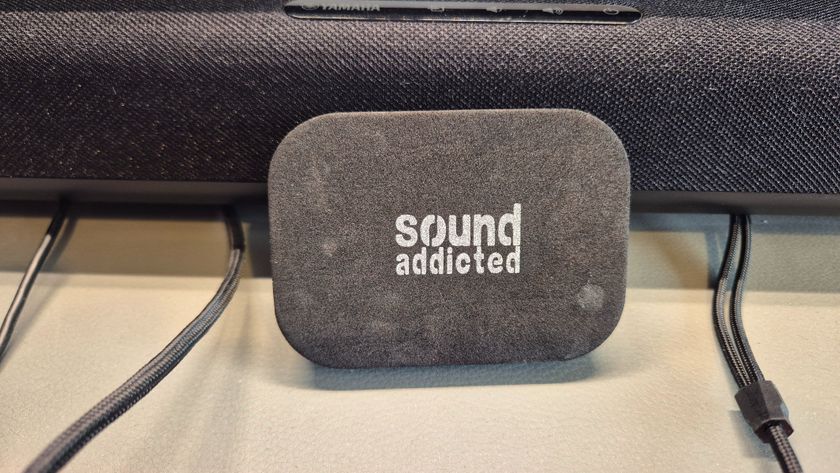 A picture of a sound addicted soundbar isolation pad resting against a Yamaha soundbar on a gaming desk