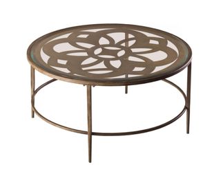 A glass top and metal coffee table with patterned detail
