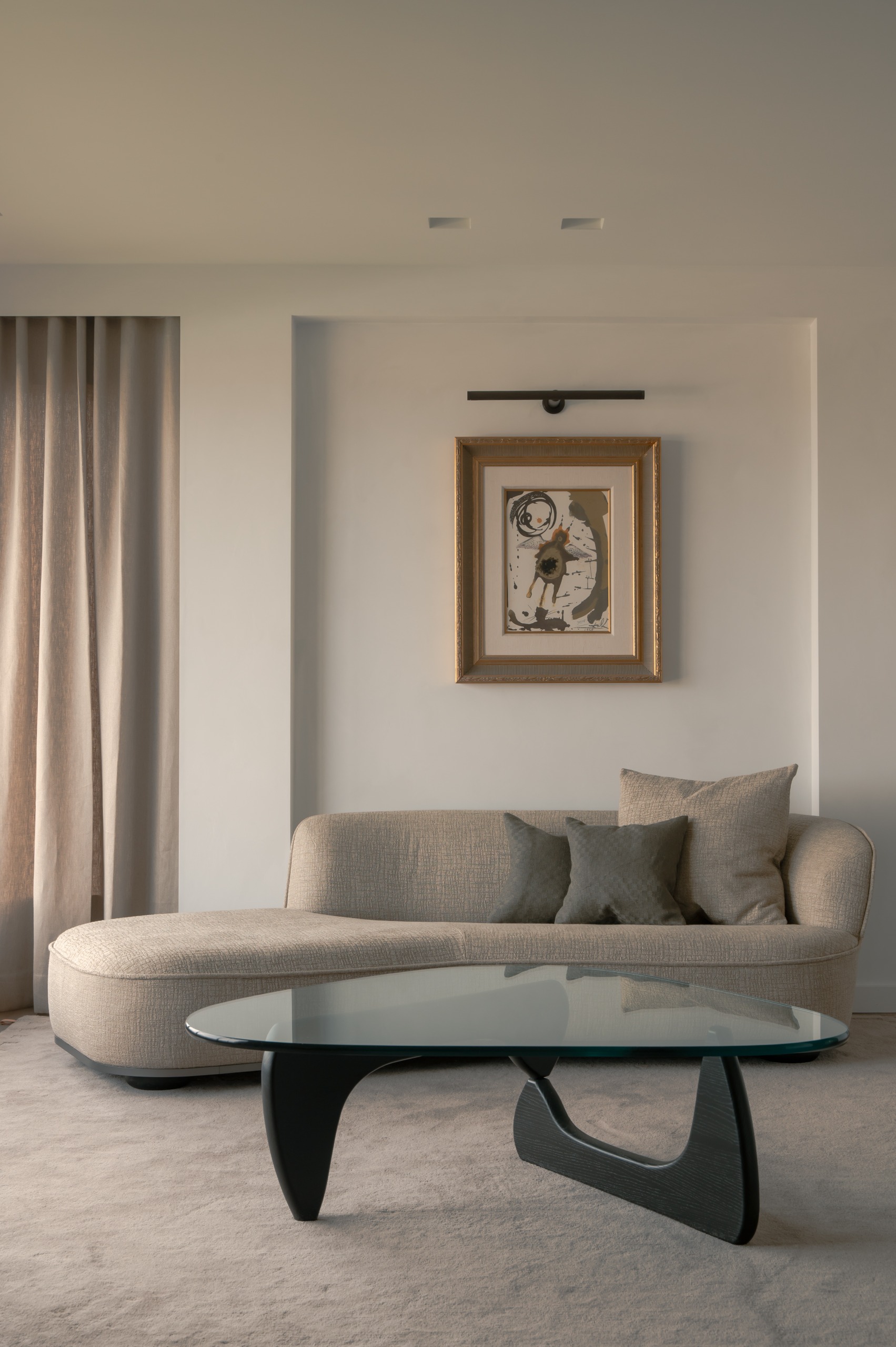 cozy living room with a day bed, a glass coffee table and a piece of art with an art light