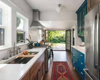 Galley kitchen with color pop accents leading to decking and garden