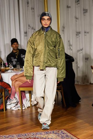 Woman on Division runway wearing bomber jacket and head scarf