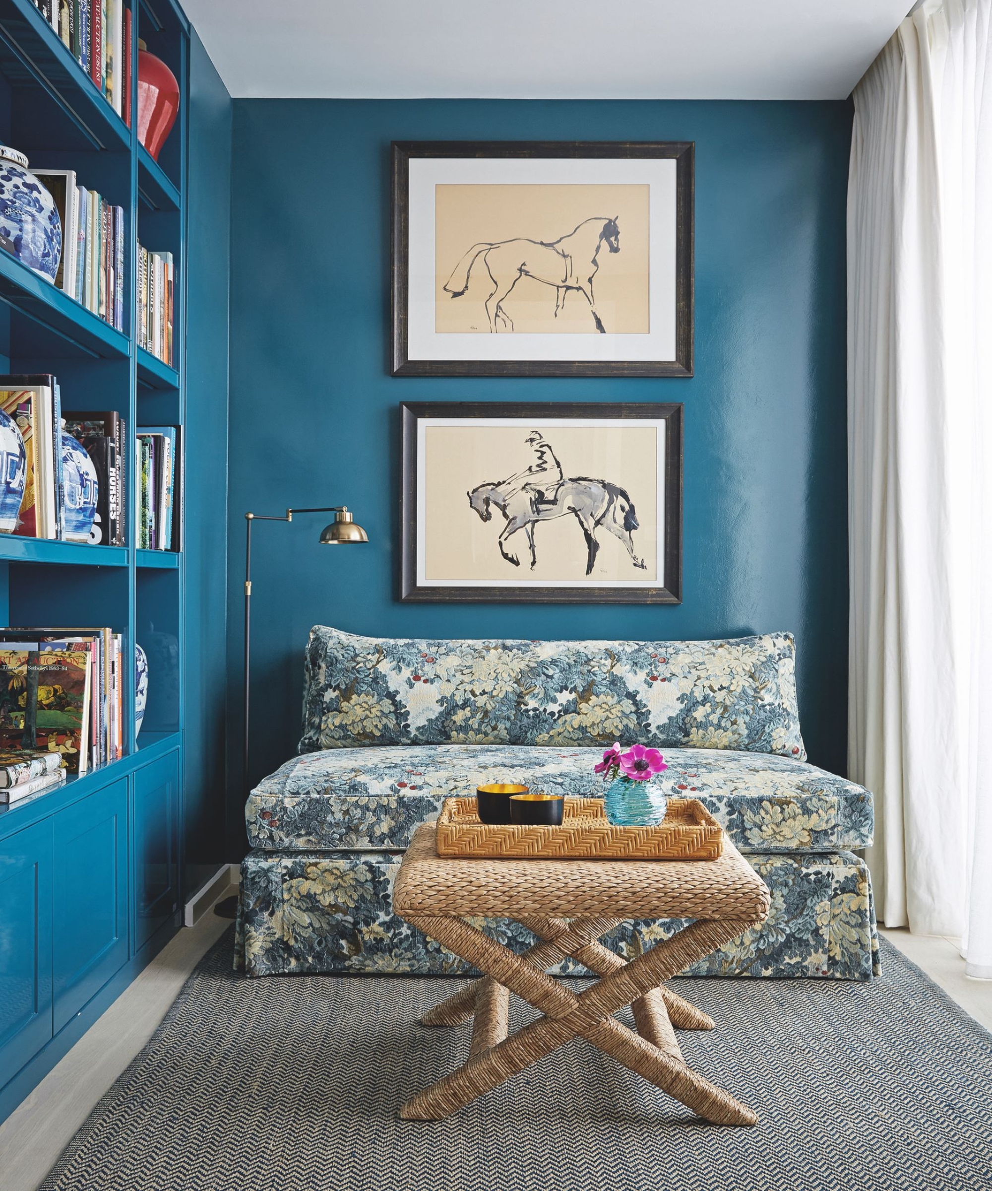 teal painted living room with floral sofa, coffee table and book shelves