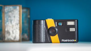 Lifestyle photo of the Flashback camera against a light blue background