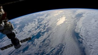 the view of blue waters and white clouds on Earth from a space station high above the planet