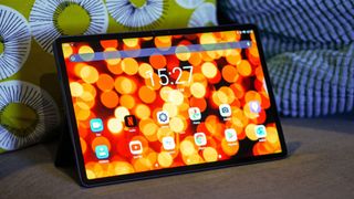 A Lenovo Tab P11 Pro with the screen on, resting against a cushion