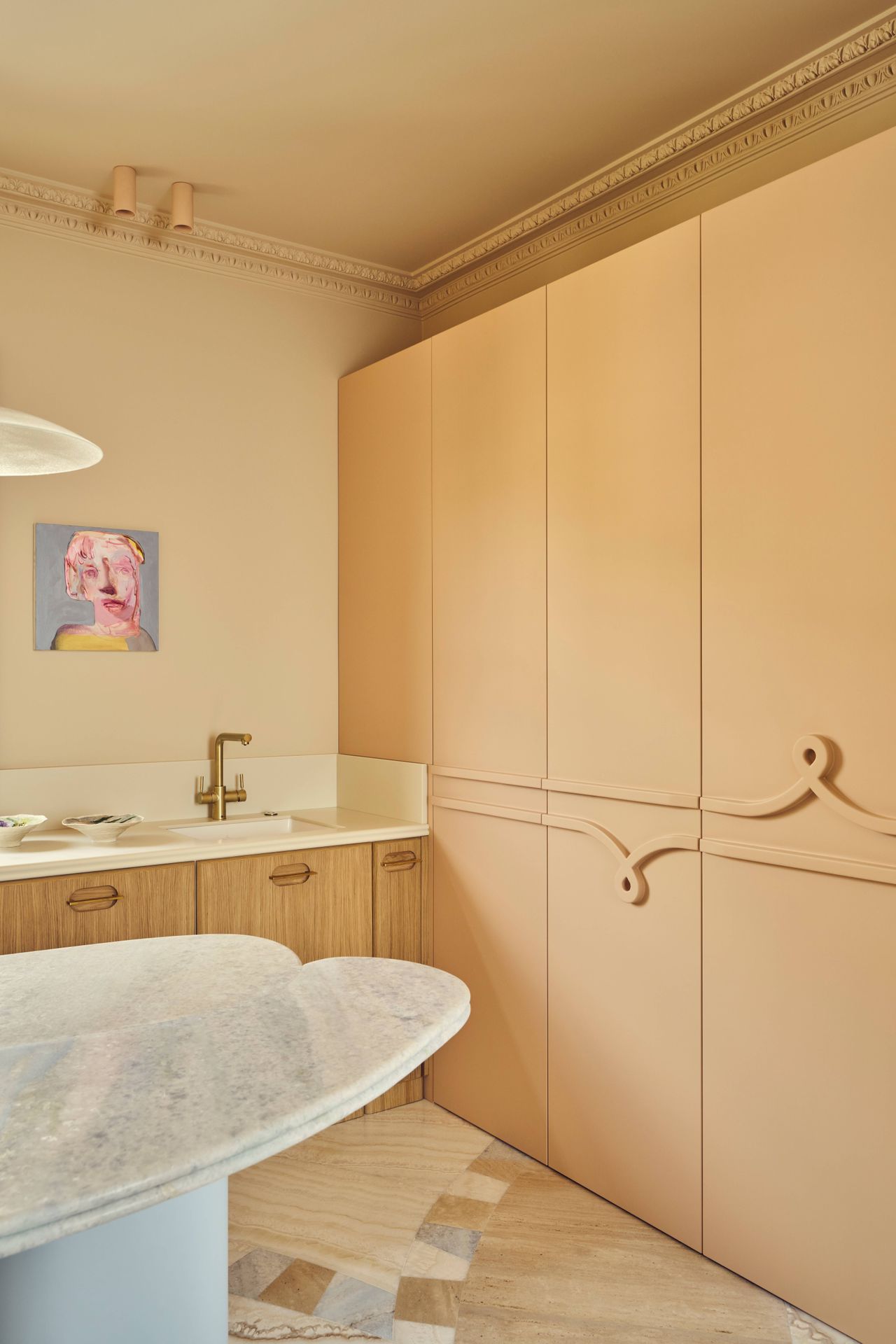 Batiik Studio-designed kitchen area featuring a rounded peach-lined archway, a custom marble dining table, Scandi-style low-back stools, and a pendant light overhead.