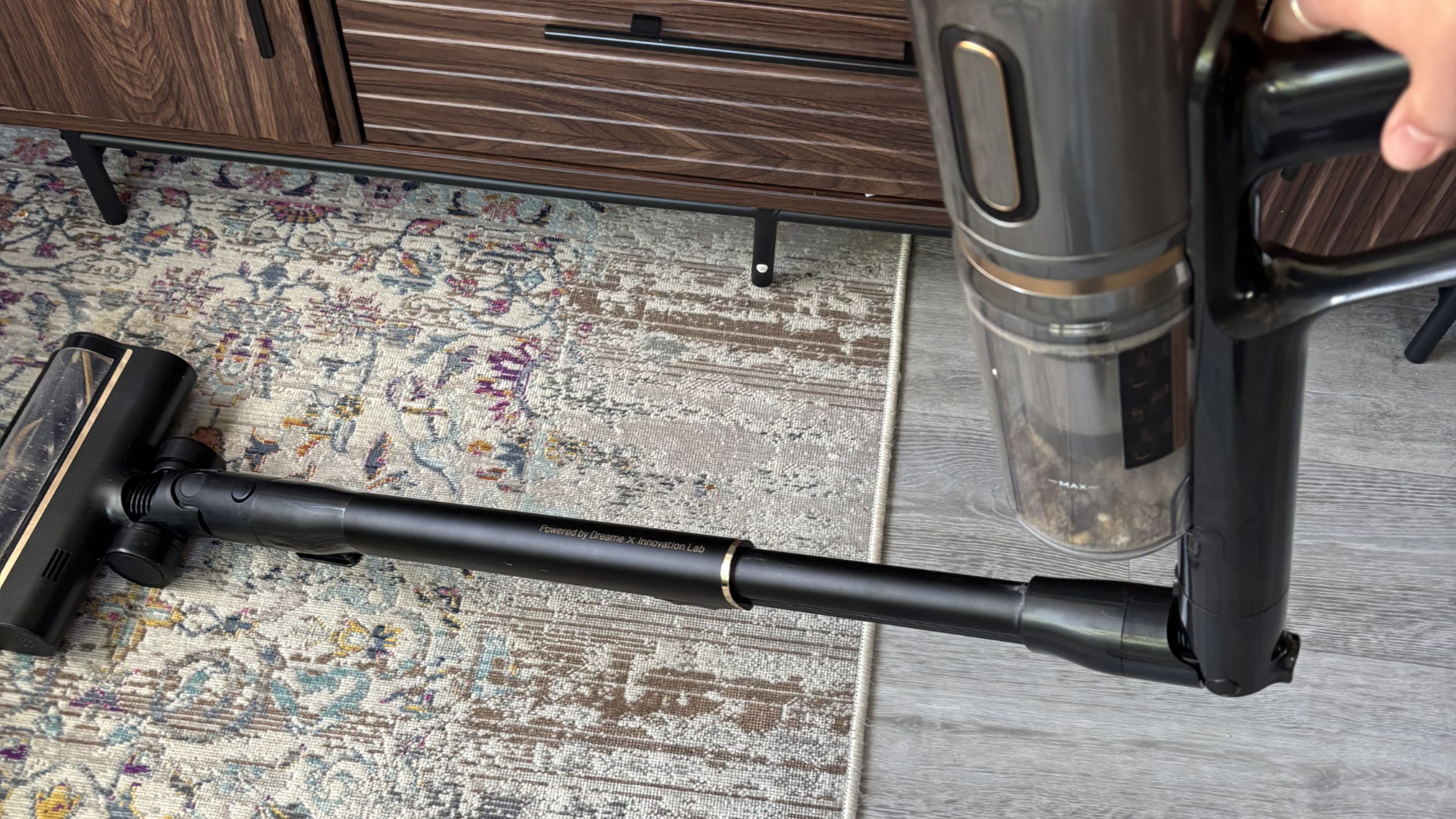The Dreame cordless stick vacuum folded down to fit under furniture in a living room