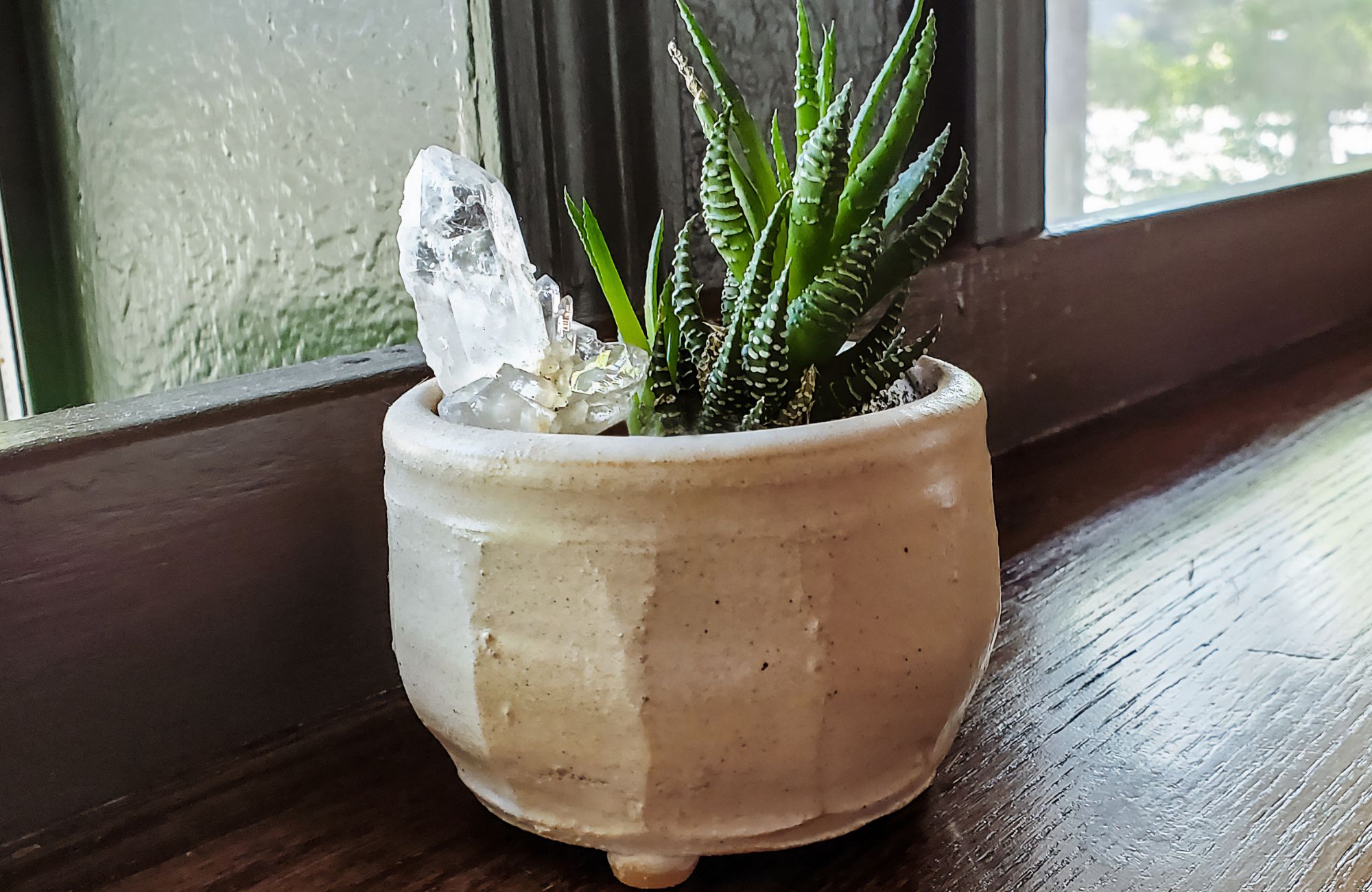 Pot of succulents and crystals sitting on wooden countertop by windows - perspective and room for copy