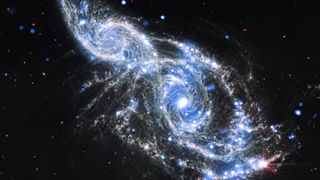Two blue and white spirals of light are intertwined in the darkness of space