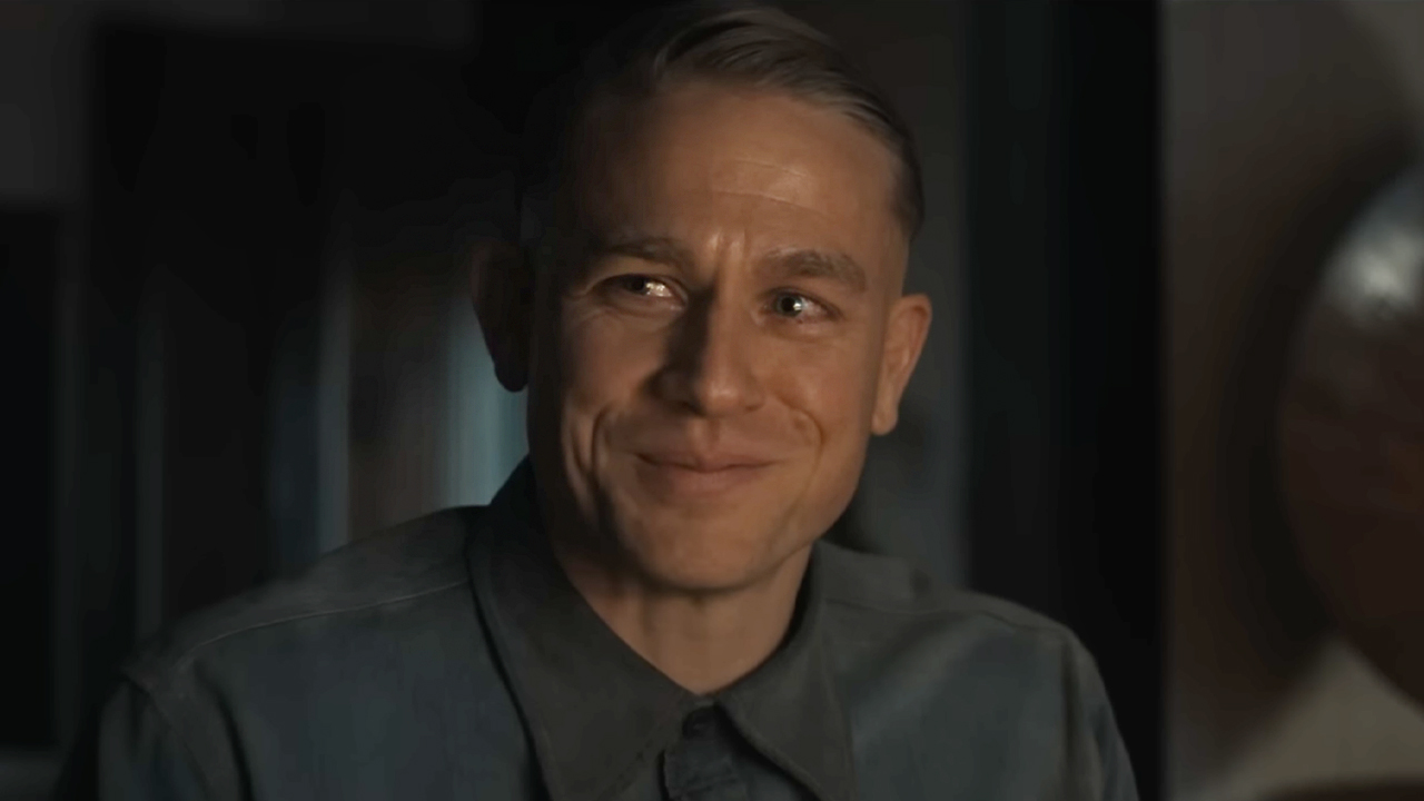 Charlie Hunnam sitting at a dinner table as Ed Gein in Monster: The Ed Gein Story. 