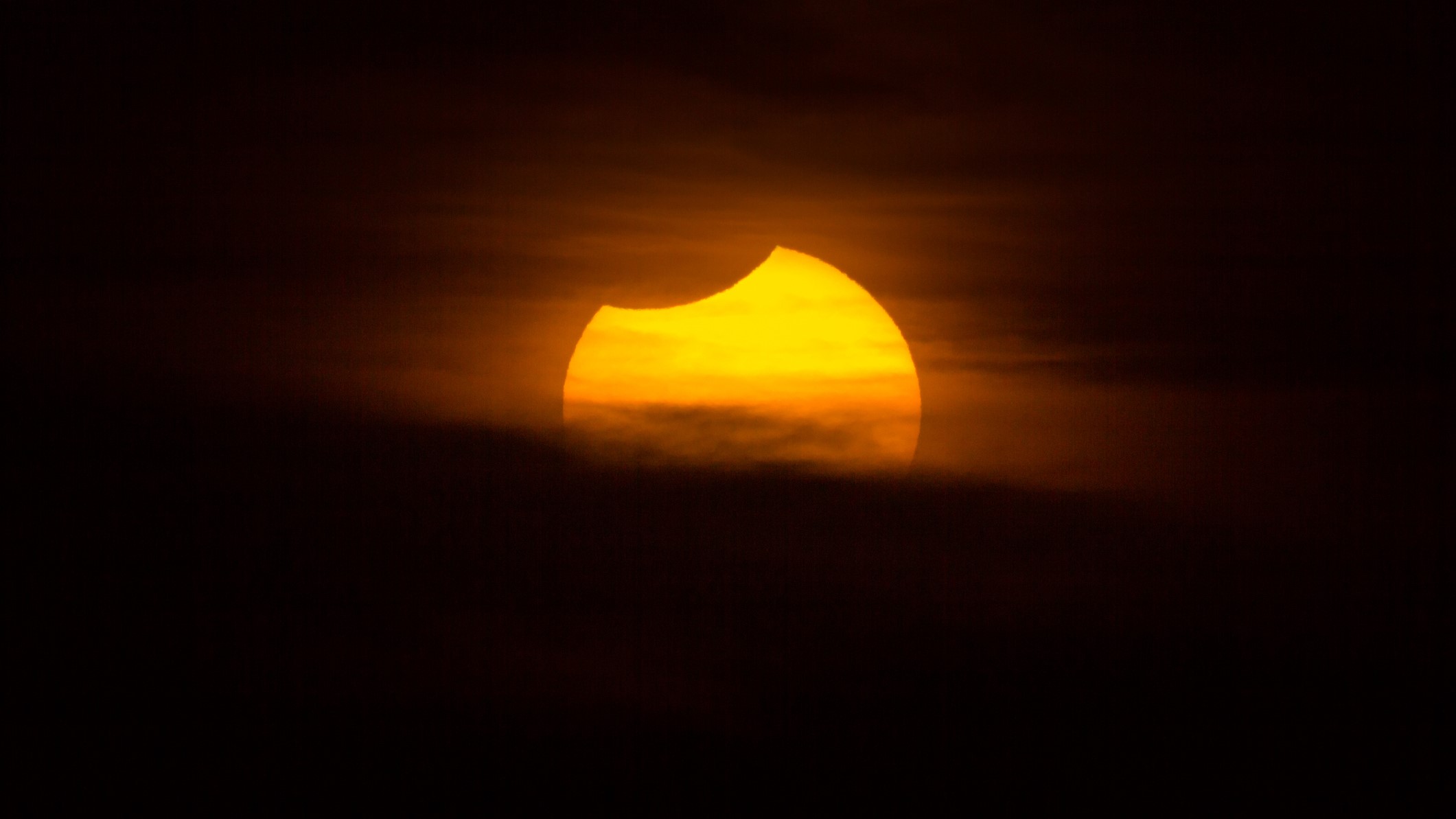 Solar eclipse observed in Montevideo, Uruguay. Image taken outdoors, no people in the image. At the same time sun is setting over the horizon, over Rio de La Plata.