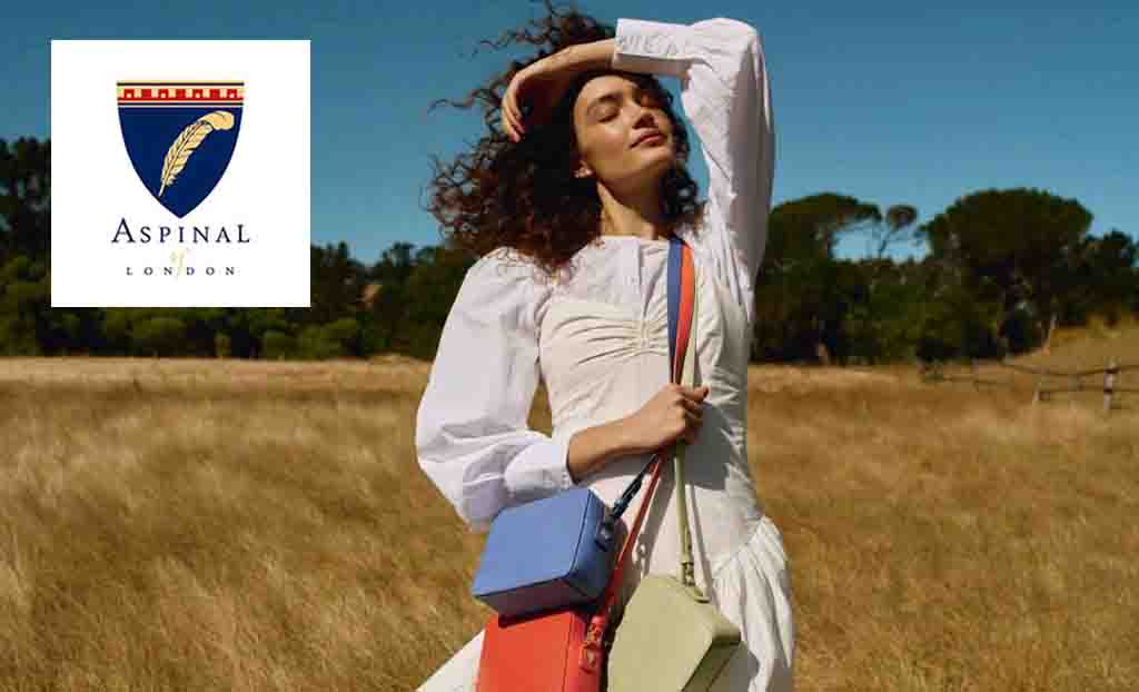 Aspinal of london logo placed over a woman posing in a field with multiple. bags 