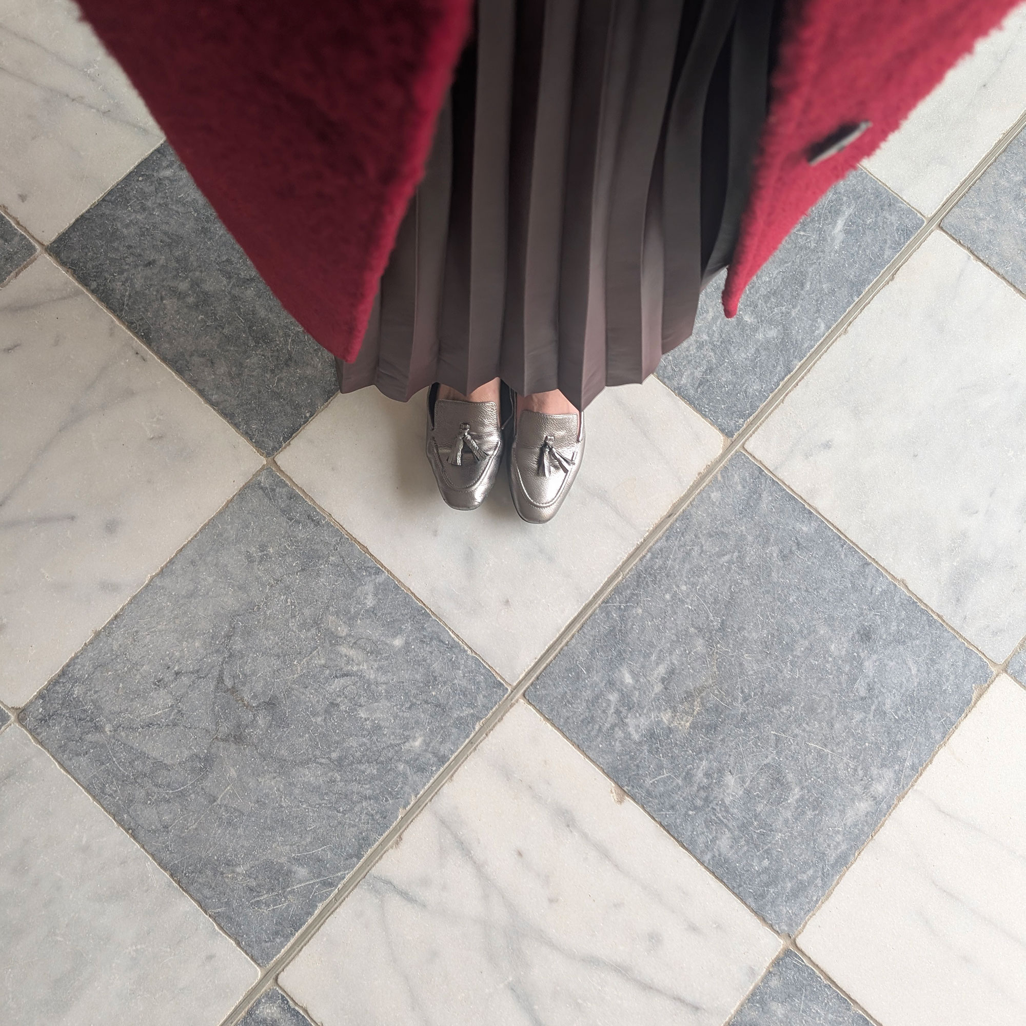 Woman in silver shoes standing on marble chequerboard floor