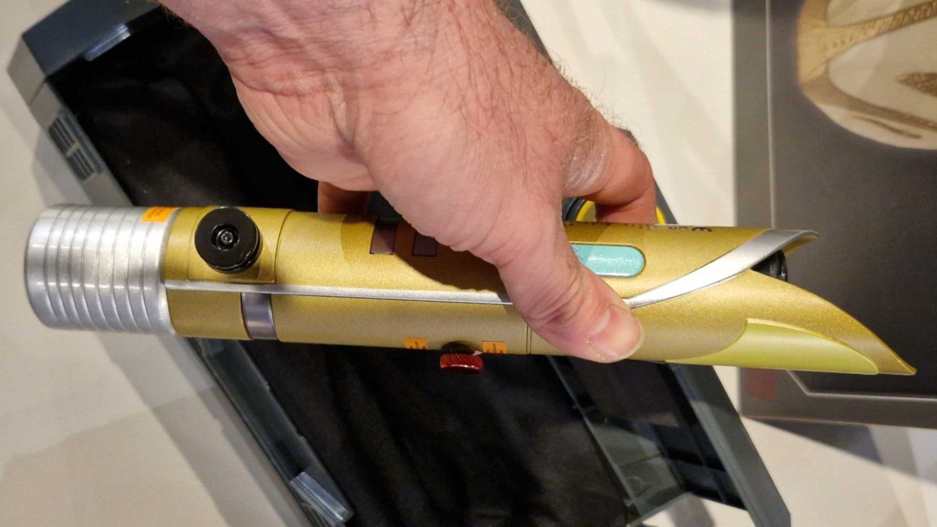 A hand holds a Star Wars lightsaber hilt