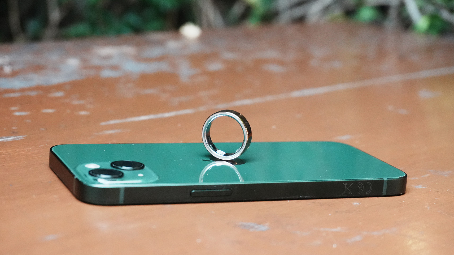 The Oura Ring 5 perched on top of a green iPhone 13