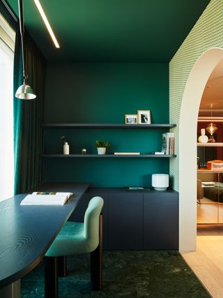 Desk area with dark green walls and dark wood furniture