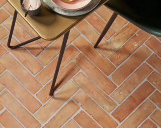 Rustic terracotta floor tiles in herringbone formation.