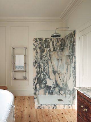 A slab stone shower in a light panelled bathroom