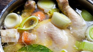 Chicken in soup broth with vegetables like onion and carrots