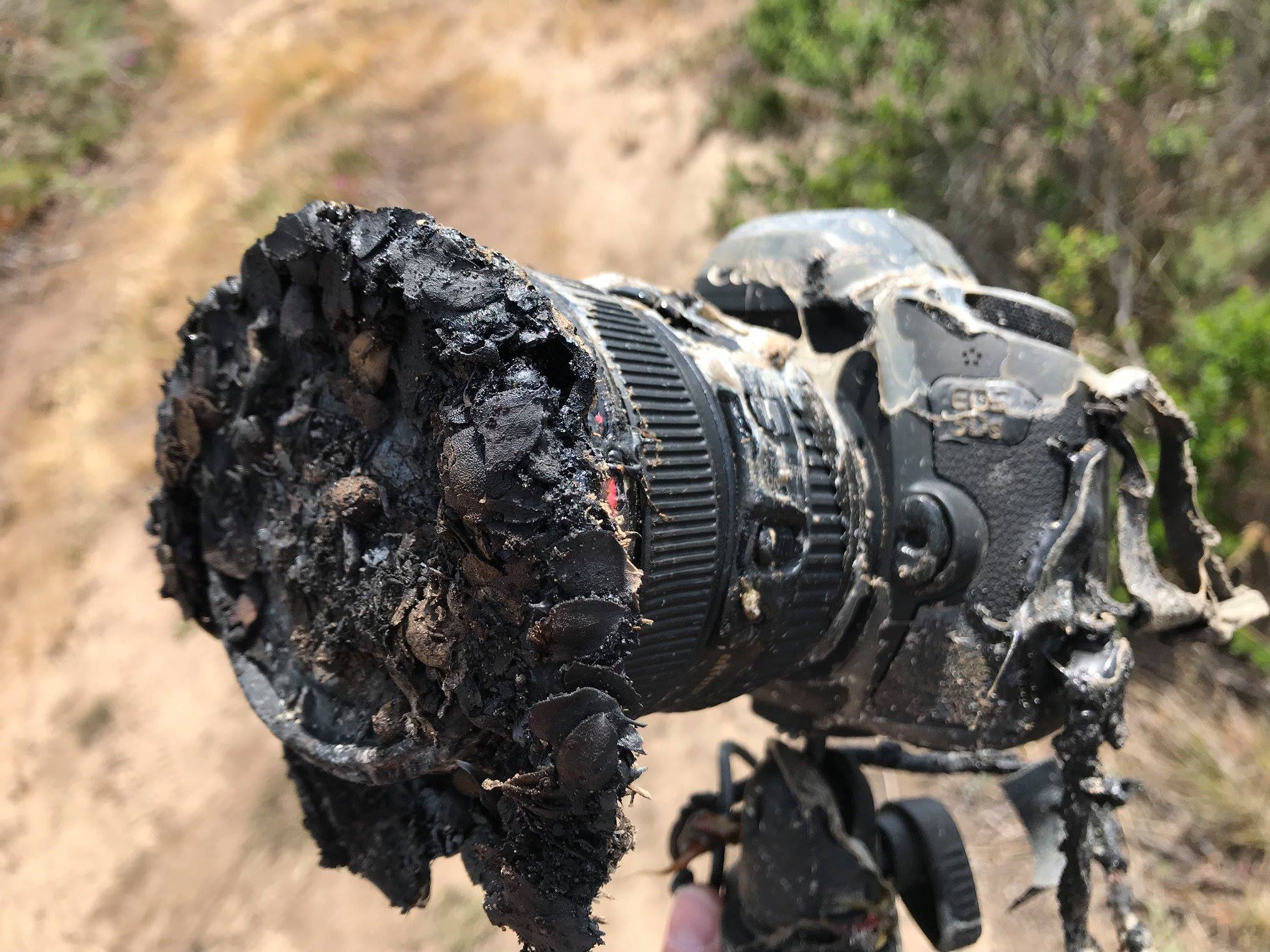 Fotograf NASA Bill Ingalls opublikował to zdjęcie stopionego aparatu Canon po tym, jak został zniszczony przez pożar zarośli wywołany wystrzeleniem rakiety SpaceX Falcon 9 w bazie sił powietrznych Vandenberg w Kalifornii 22 maja 2018 r. Falcon 9 wystrzelił bliźniaczą GRACE- Satelity FO i pięć satelitów komunikacyjnych Iridium Dalej.